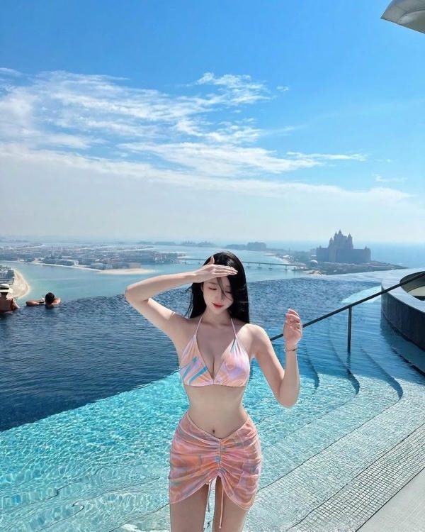 Cô gái bikini bước đi dọc bờ biển.