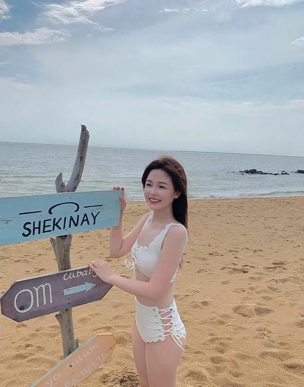 Cô gái bikini đứng bên bờ biển xanh ngọc.