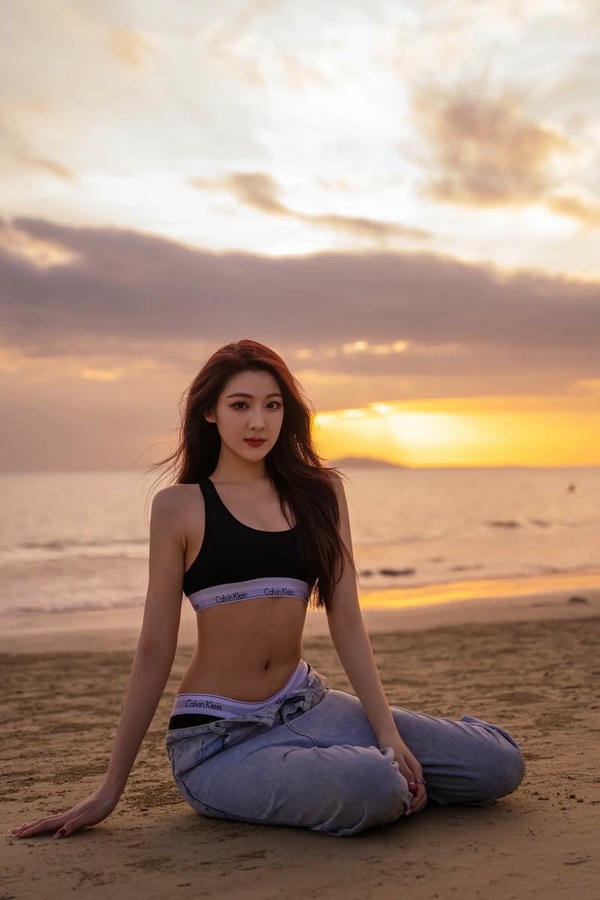 Cô gái bikini đứng trên bãi biển lúc hoàng hôn.